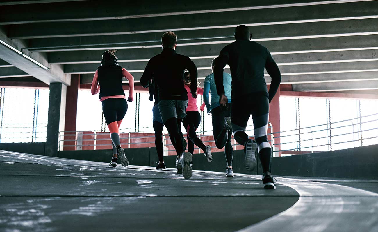 A group of people running in a parking garage.