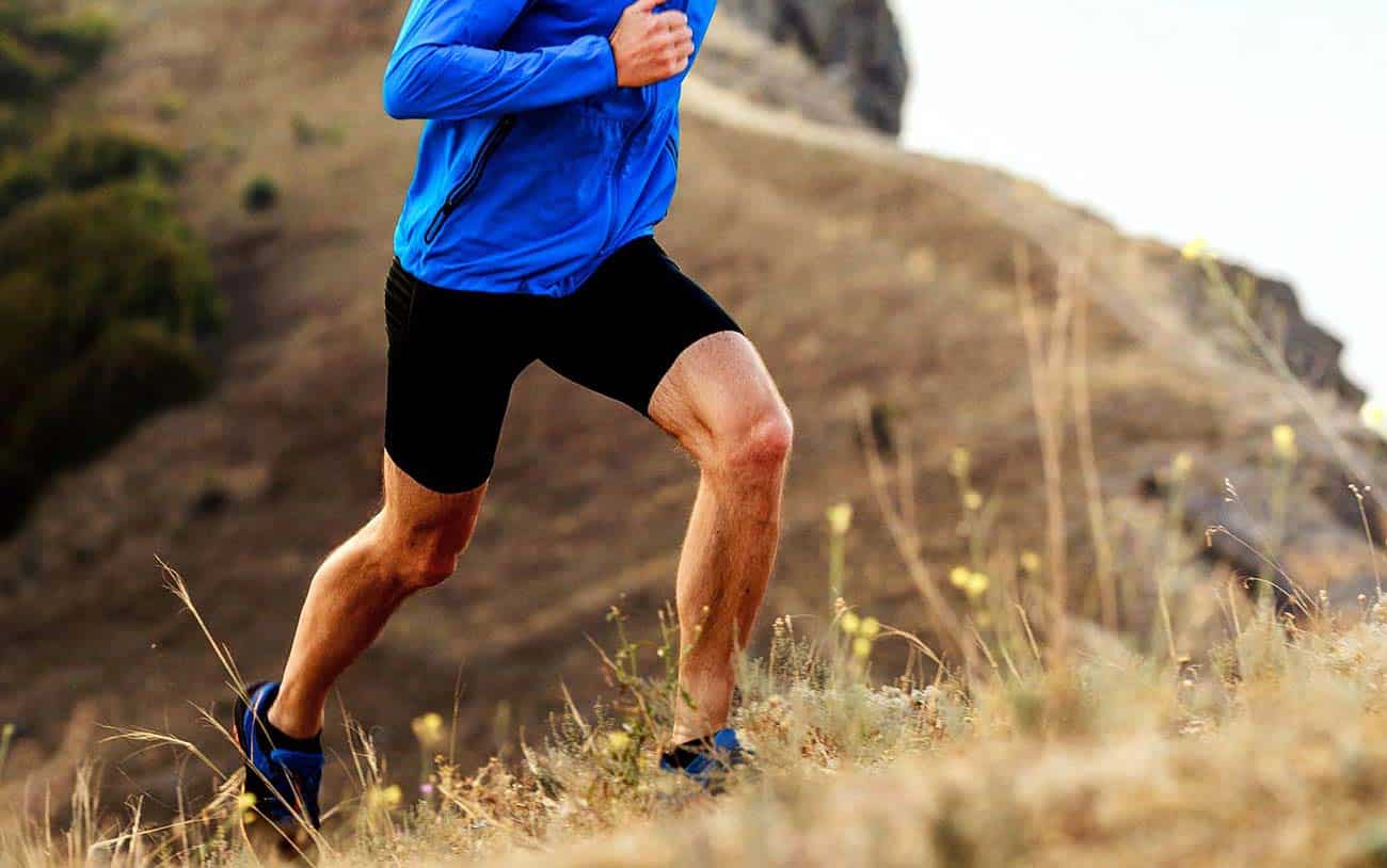 A man in a blue shirt is running on a hill.