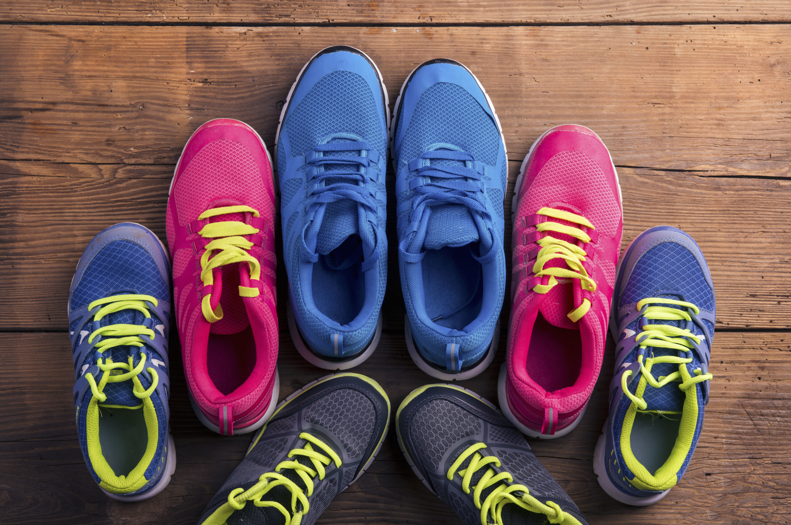 Looking for colorful running shoes for purchasing? Check out these vibrant kicks on a wooden floor.