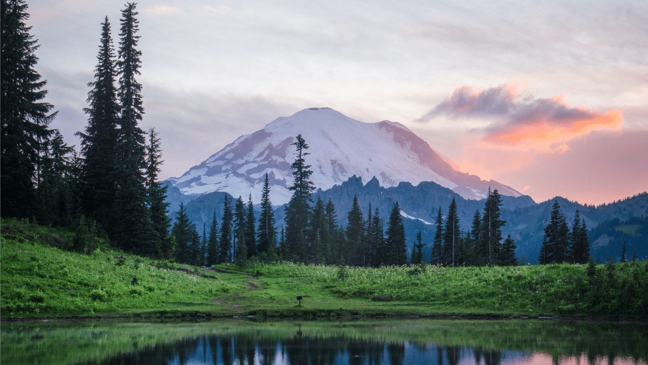 Mount Rainier is reflected in a lake at sunset.