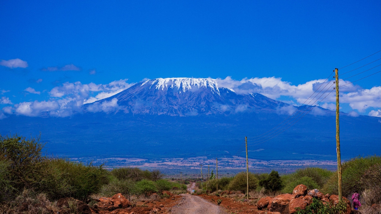 A marathon runner on a dirt road with Mount Kilimanjaro in the background.