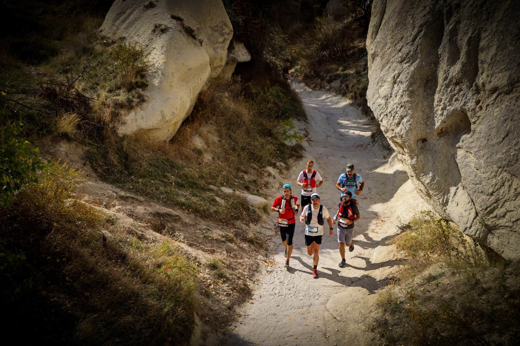 A group of people engaged in ultrarunning on a trail through a rocky area, learning important lessons along the way.