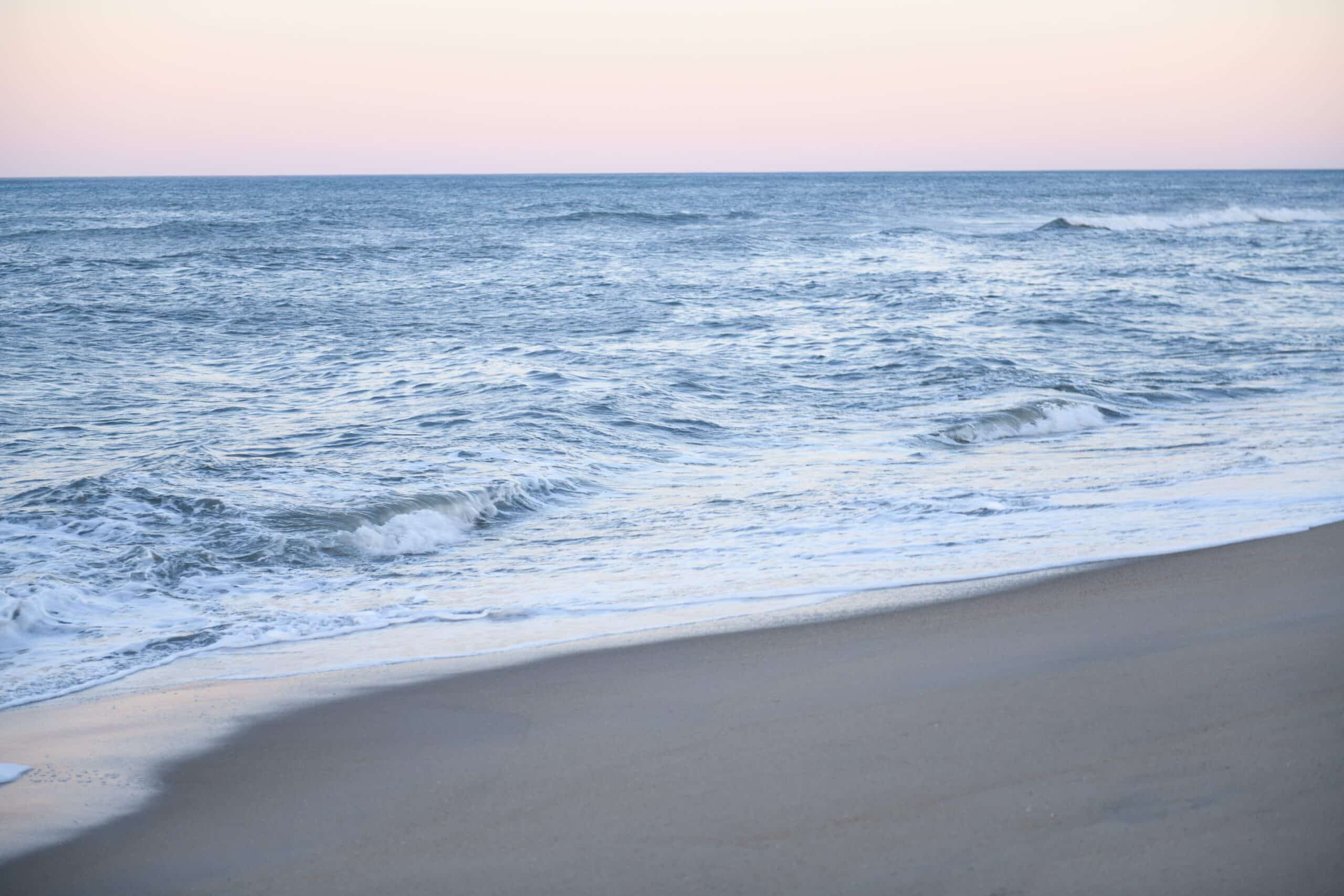 A man is standing on a sandy beach near the ocean.