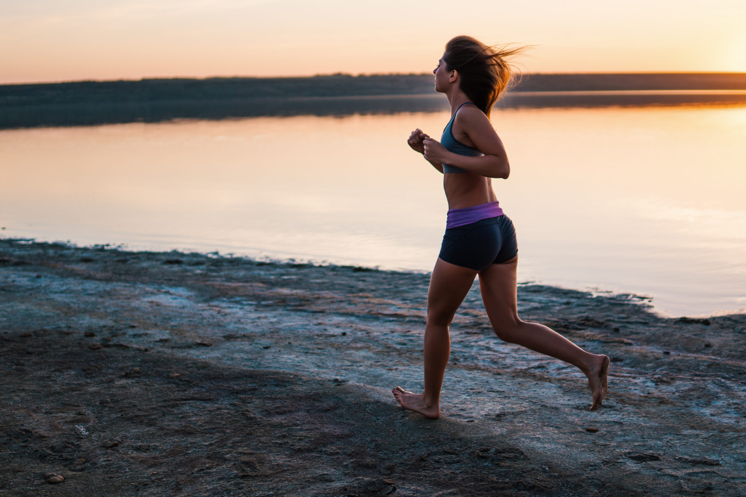 A woman is combining her vacation with running a race near a lake at sunset.
