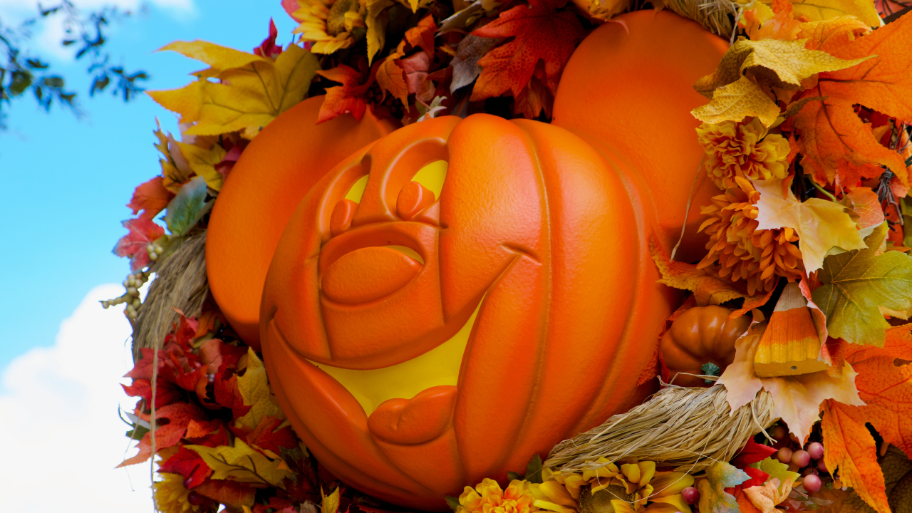 A Mickey mouse pumpkin adorned with a wreath of leaves.