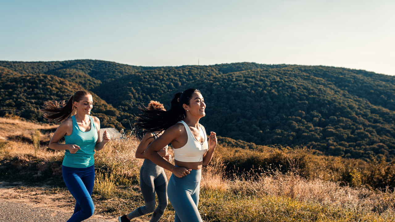 Three women participating in a marathon, jogging every stride on a mountain road.