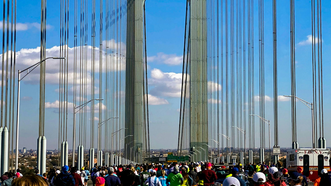 Pedestrians walking across a suspension bridge on a clear day, sparking controversy.