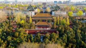 Aerial view of a traditional Chinese palace with elaborate rooftops amid lush trees, surrounded by the Beijing Half Marathon route in the background.